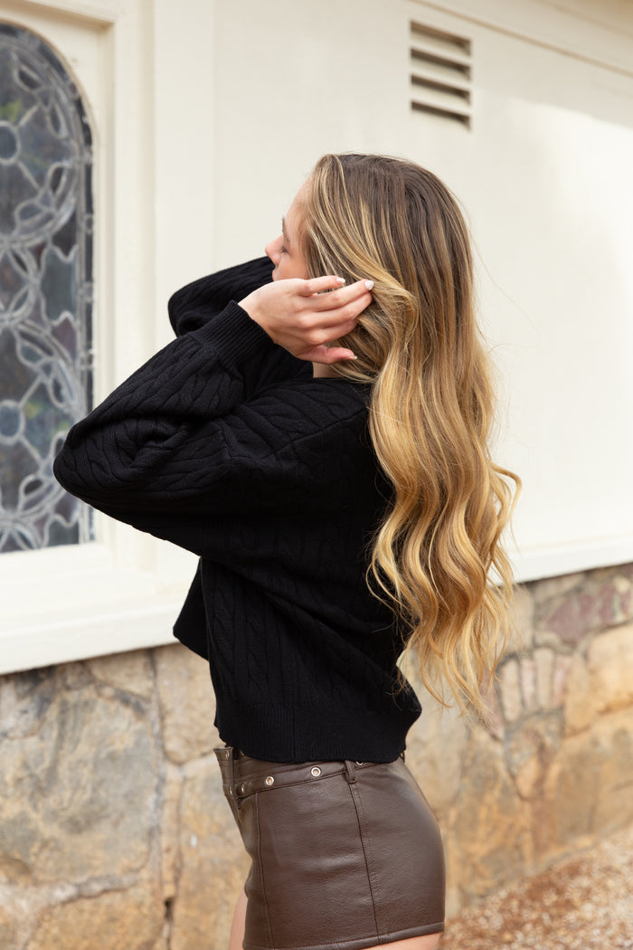 Woman adjusting her hair against a stone wall and window background