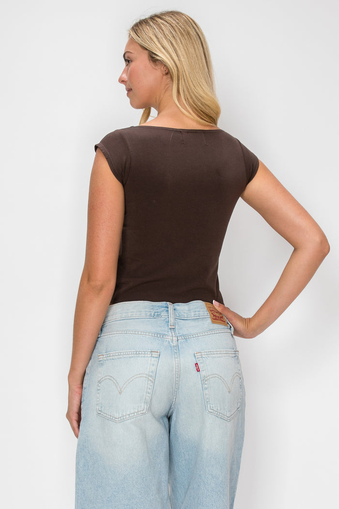 A woman shown from the back wearing a fitted short-sleeve brown top and light-wash blue jeans against a plain light gray studio background.