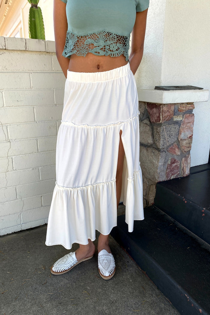 Person wearing a light blue crop top and white tiered skirt standing on steps.