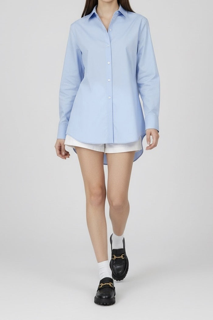 Person wearing a light blue shirt, white shorts, and black shoes on a white background