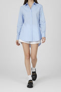 Person wearing a light blue shirt, white shorts, and black shoes on a white background