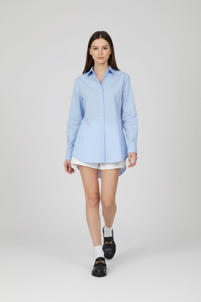 Woman wearing a light blue shirt, white shorts, and black shoes on a white background
