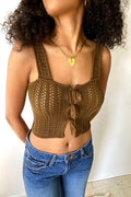 Woman wearing a brown crochet tank top and blue jeans against a white background
