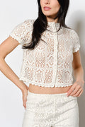 Woman wearing a white lace top and skirt against a plain background