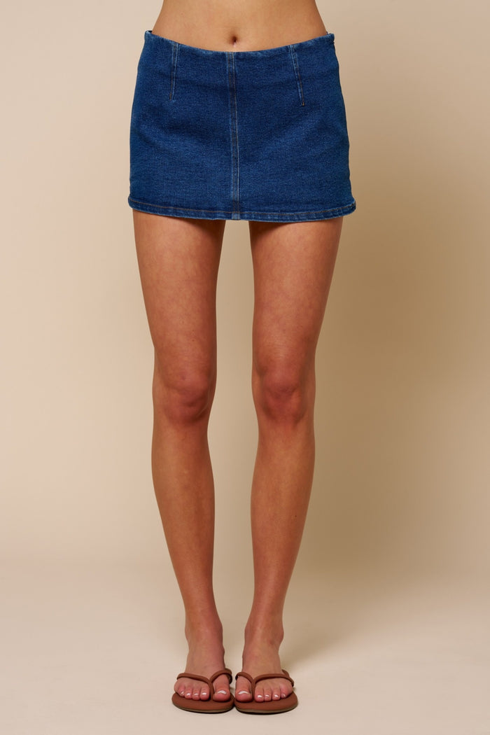 Person wearing a blue denim skirt on a beige background