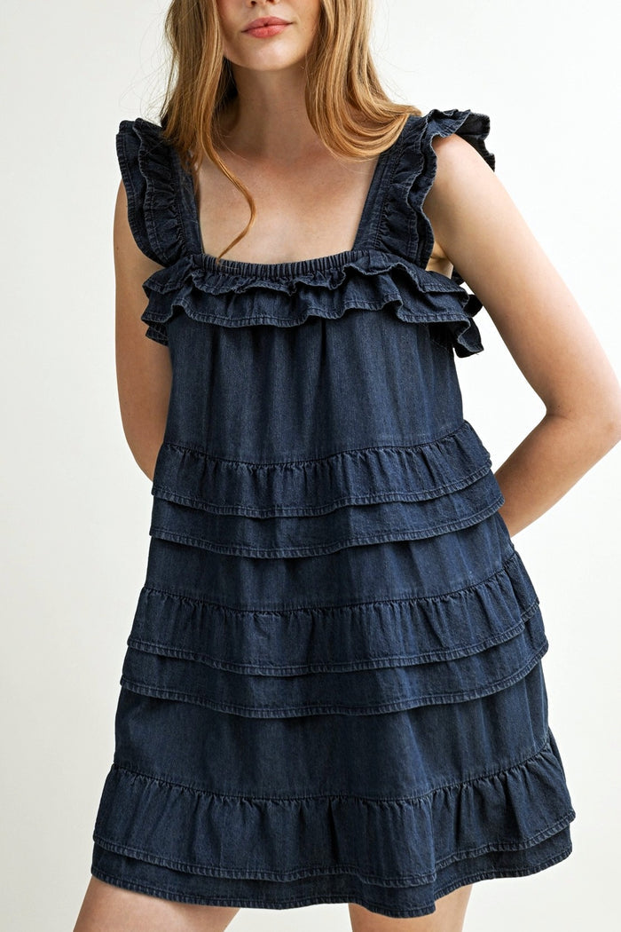 Denim dress with ruffled details on a plain background