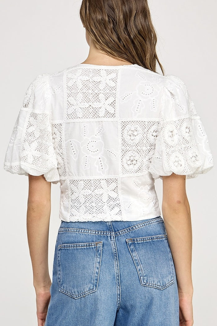 White lace top worn by a person on a plain background
