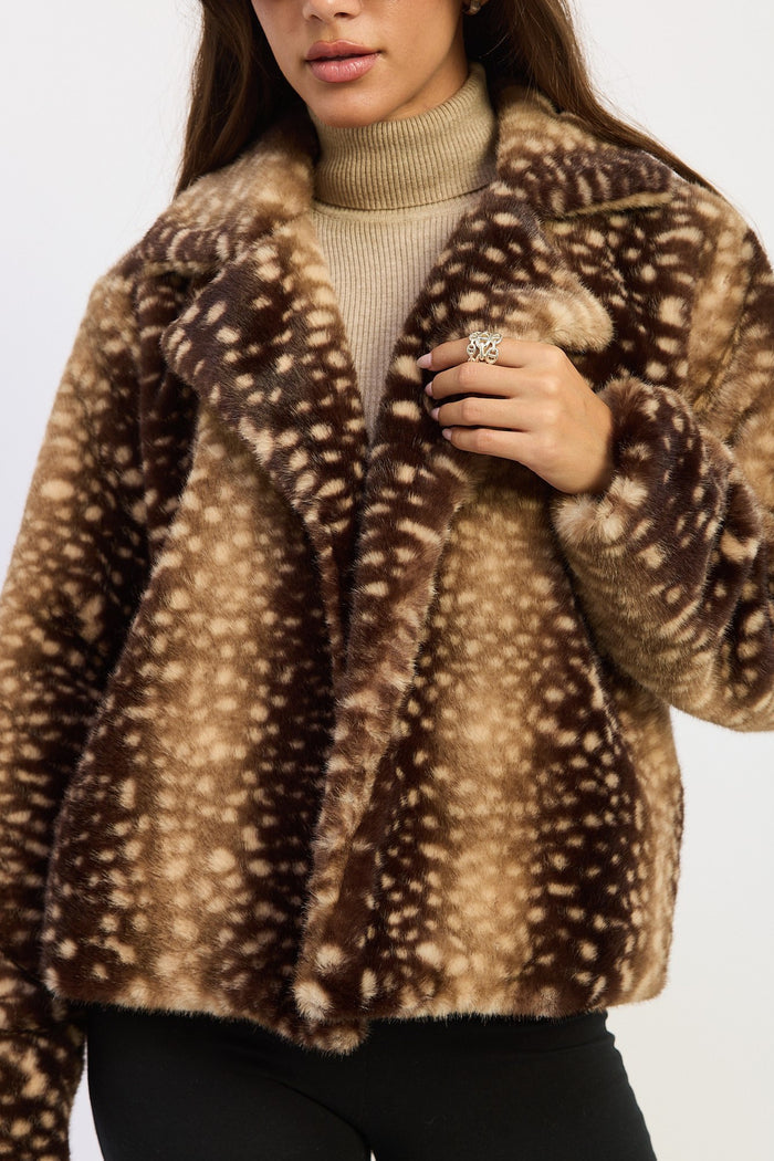 A close-up of a woman wearing a brown faux fur jacket with a white spotted deer print pattern, layered over a beige turtleneck sweater.