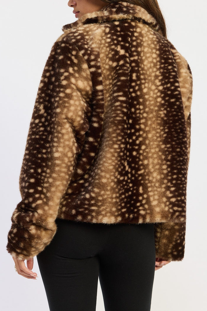 A woman shown from the back wearing a brown faux fur jacket with a beige and white spotted deer-print pattern, paired with black pants, against a plain white background.