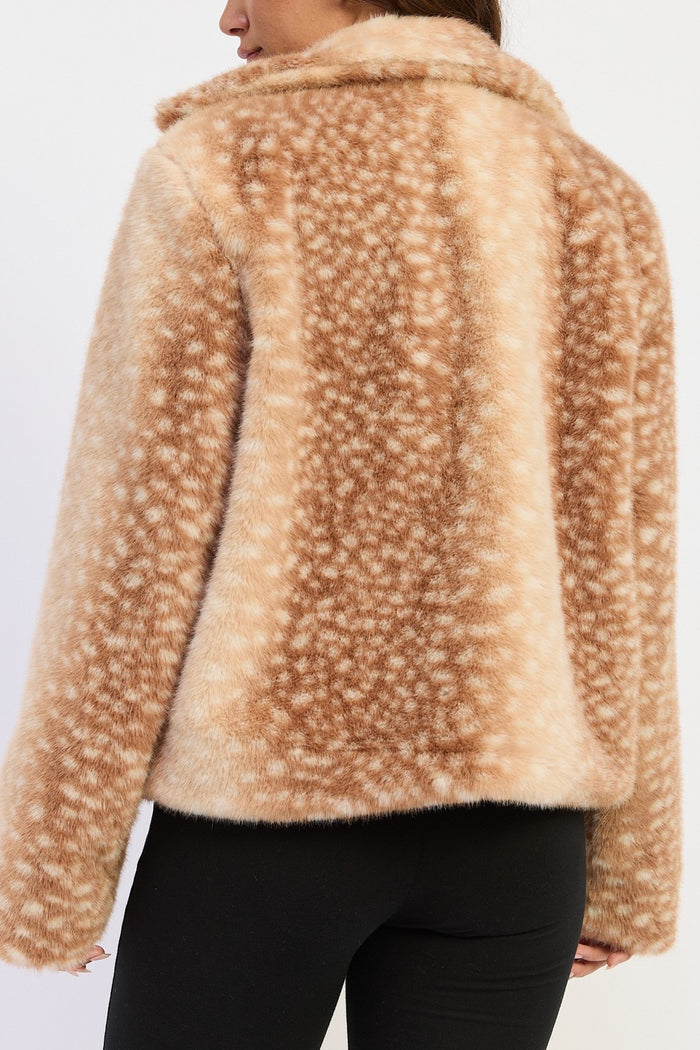 A close-up back view of a model wearing a beige faux fur jacket with a white spotted deer-antler pattern, paired with black leggings.