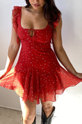 Woman wearing a red dress with white polka dots against a plain background