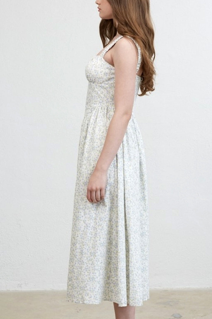 Woman wearing a white floral dress against a plain background