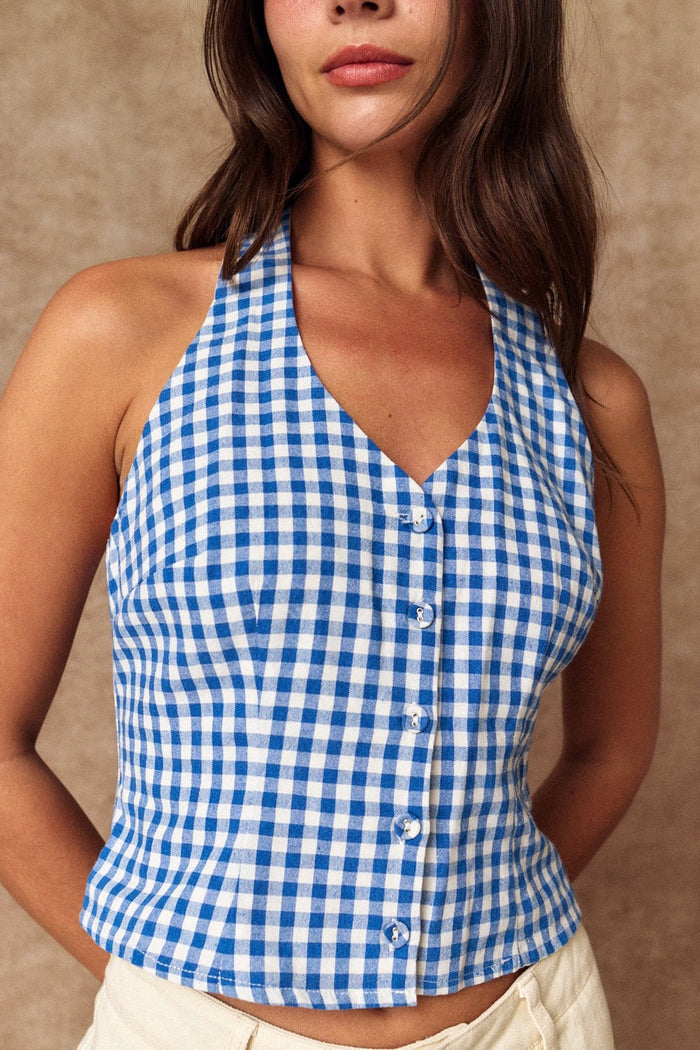 Woman wearing a blue and white checkered halter top against a beige background