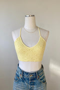 Yellow lace crop top on a mannequin with a plain background