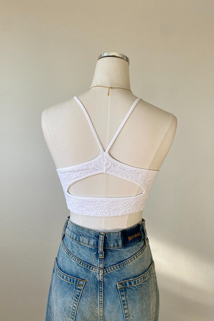 White lace crop top on a mannequin with a plain background