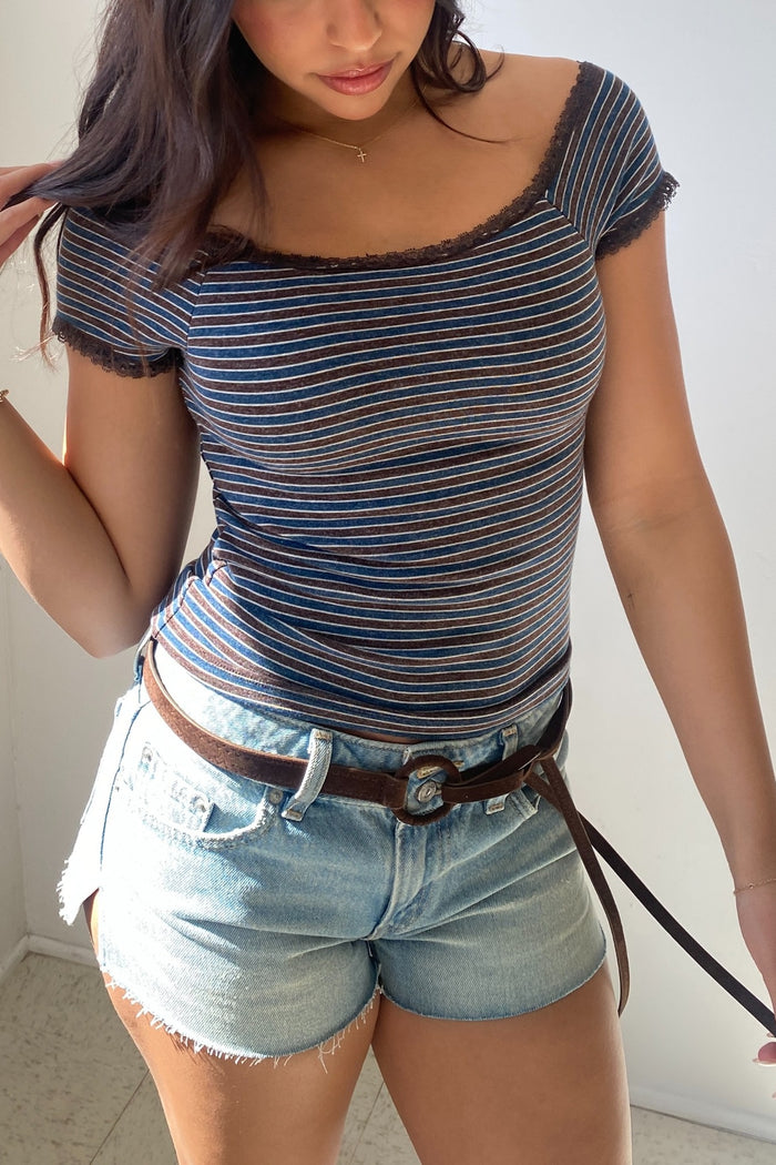 Woman wearing a striped top and denim shorts with a belt.