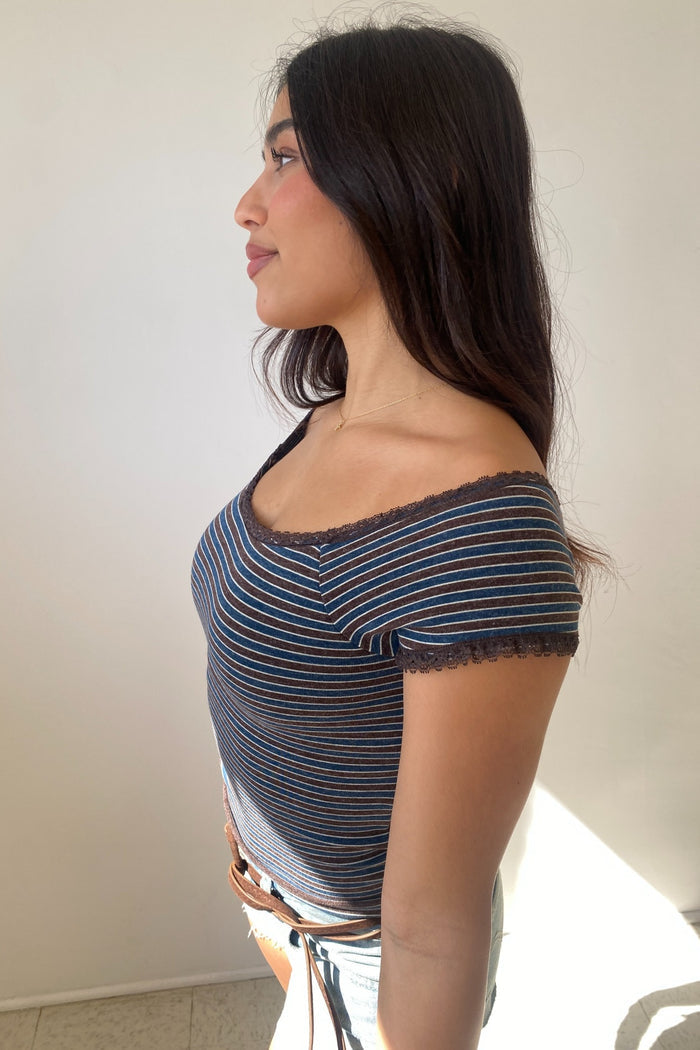 Woman wearing a striped top with lace trim against a plain background
