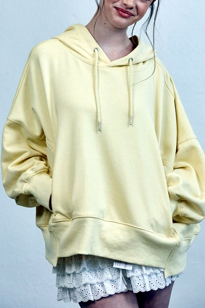 Person wearing a light yellow hoodie with a plain background