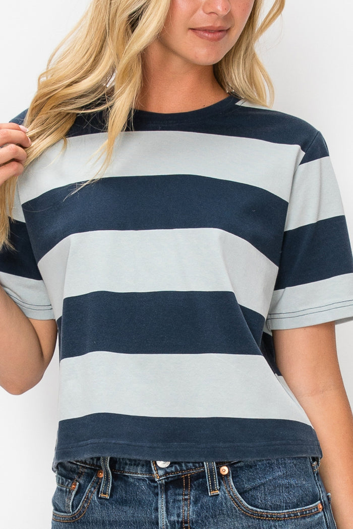 A woman wearing a short-sleeve crewneck t-shirt with horizontal navy blue and light gray stripes, paired with blue jeans.
