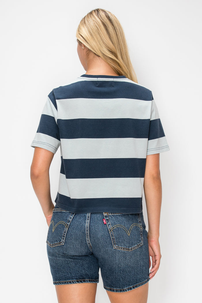 A woman shown from the back wearing a short-sleeve striped t-shirt with navy blue and light gray horizontal stripes, paired with denim shorts, against a plain white background.