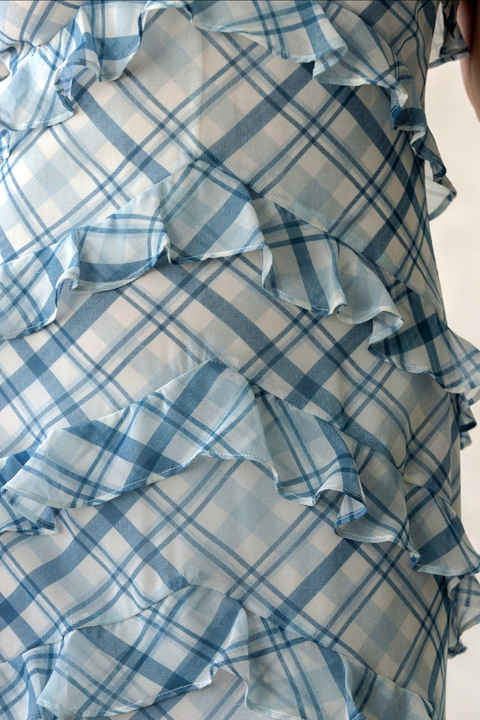 Blue and white plaid dress with ruffled layers on a neutral background