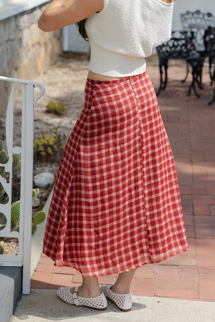 Person wearing a red and white checkered skirt outdoors.