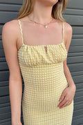 Person wearing a yellow checkered dress against a gray background