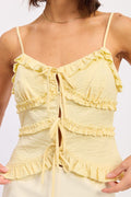 Yellow ruffled top worn by a person on a white background
