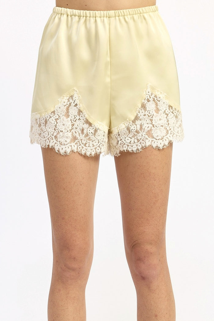 Light yellow shorts with lace trim on a white background