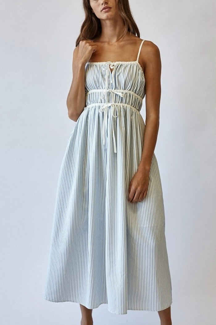 Woman wearing a white and blue striped dress against a plain background