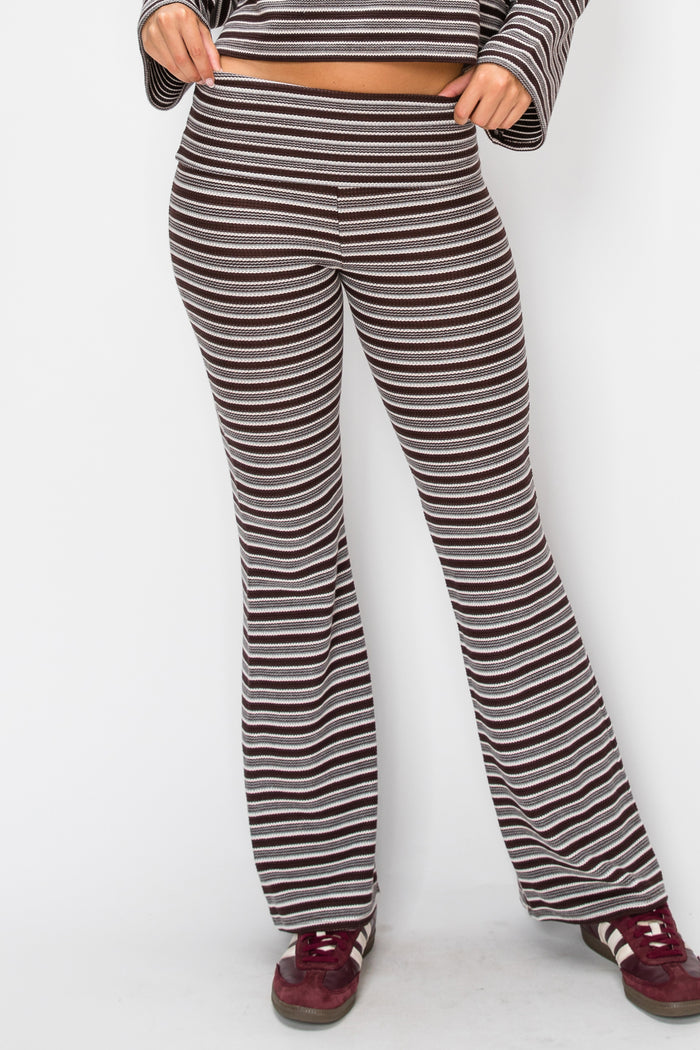 A person wearing high-waisted, wide-leg striped pants in brown and white, paired with a matching striped crop top and burgundy sneakers, shown against a plain white background.