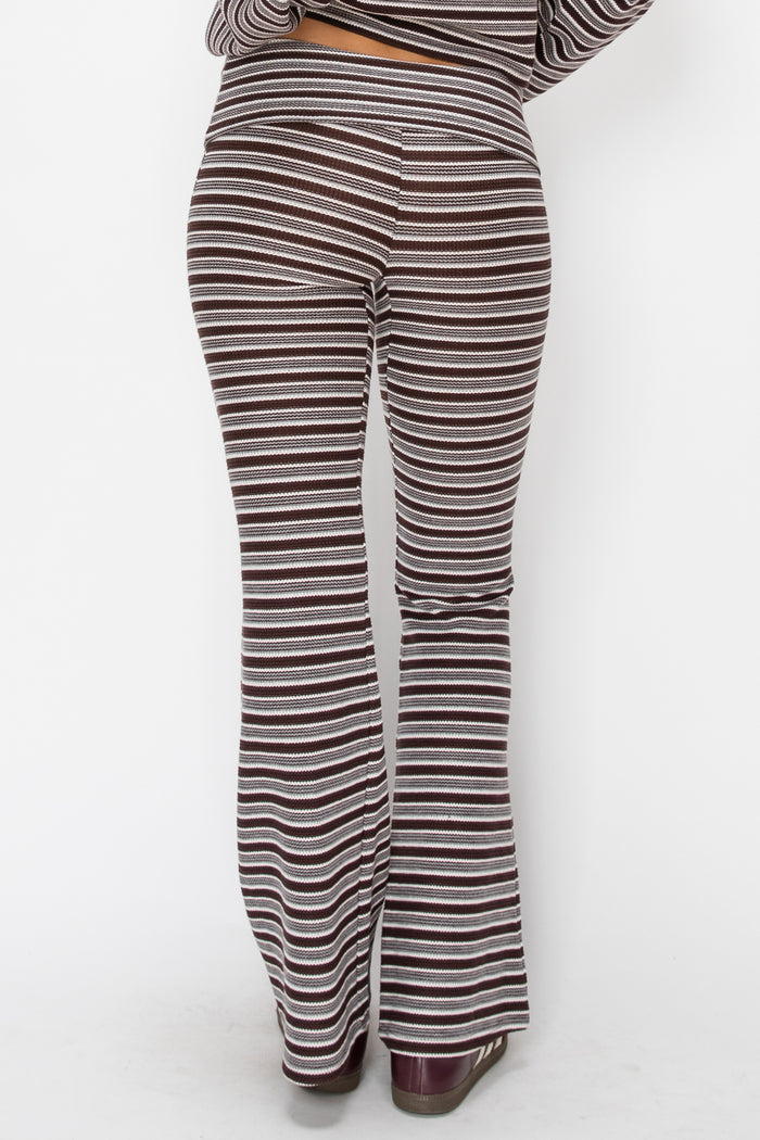 A person shown from the back wearing striped flared pants in brown, beige, and white, with a matching striped top partially visible.