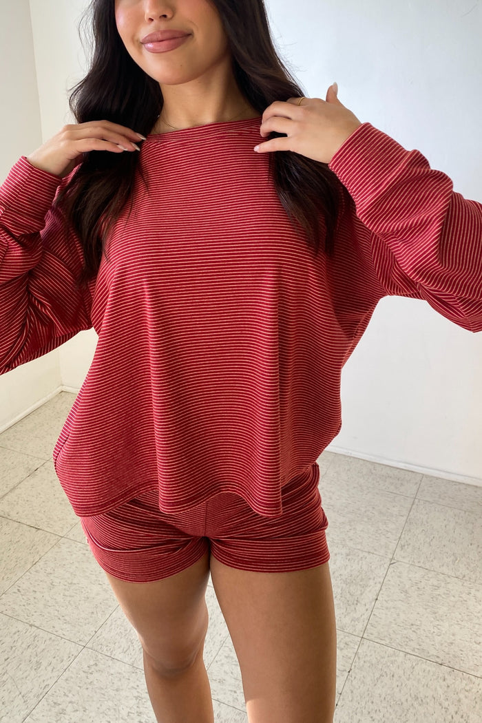 Person wearing a red ribbed sweater and shorts set indoors.