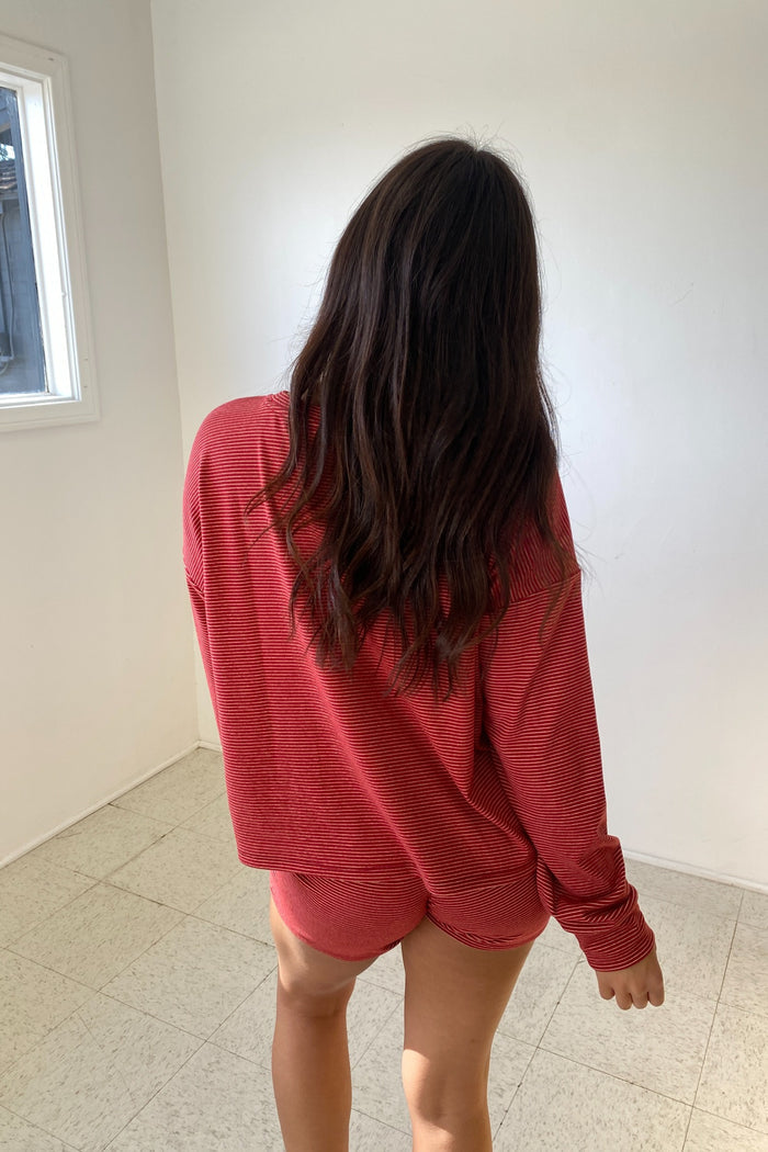 Person wearing a red outfit standing in a room with white walls and tiled floor.