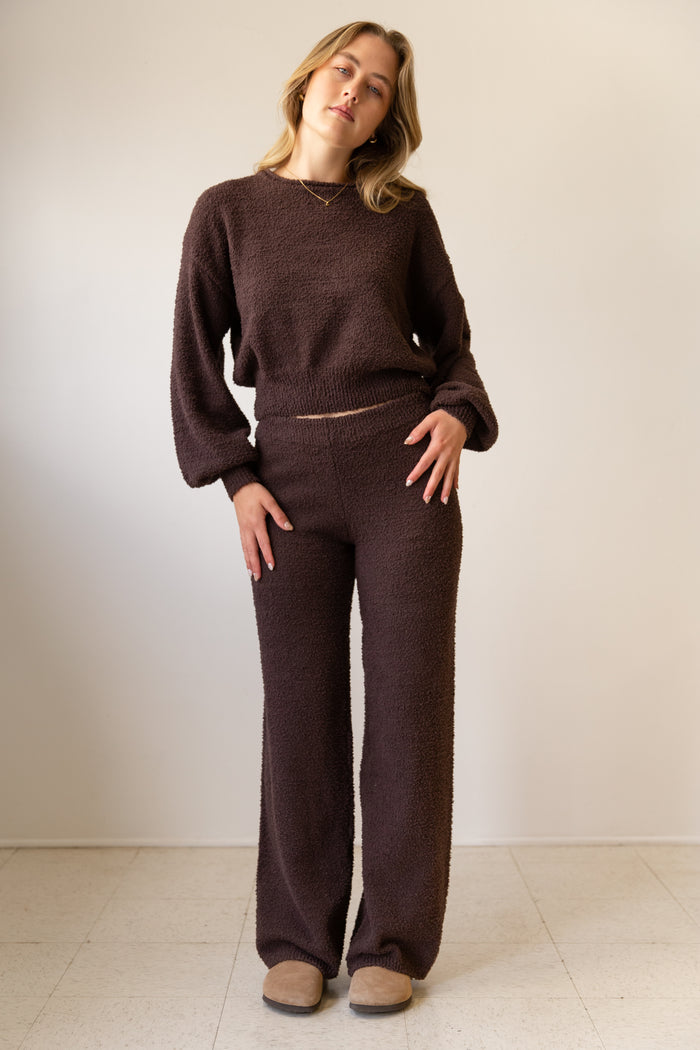 Woman wearing a brown knit outfit against a plain background