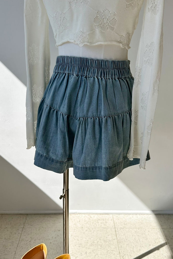Blue denim shorts on a mannequin against a white wall.