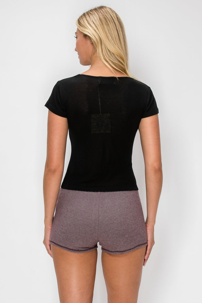 A woman shown from the back wearing a black short-sleeve top and mauve-gray textured athletic shorts against a light gray studio background.
