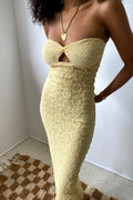 Woman wearing a yellow strapless dress with a plain background
