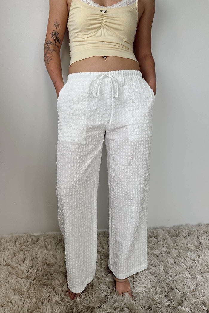 Person wearing a yellow top and white checkered pants on a neutral background